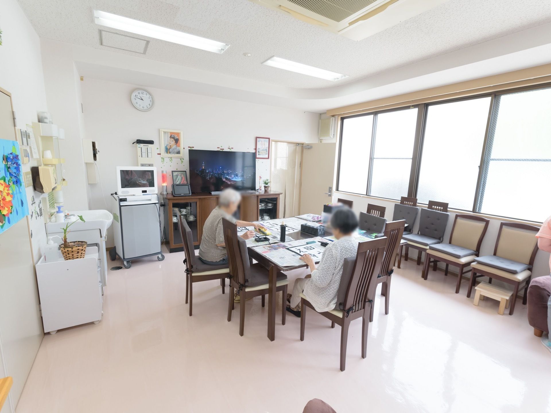 白で統一された明るい共有スペースである。テーブルや椅子、大型液晶テレビ、パソコン、洗面スペースが完備されている。