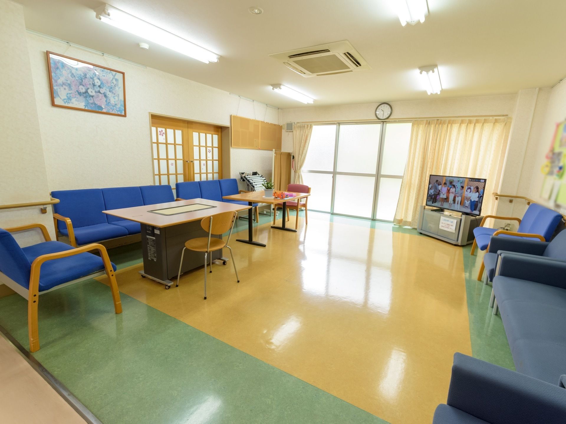 日当たりのよい開放感のある談話コーナーである。ソファや大型液晶テレビ、新聞、テレビゲーム、手すりが完備されている。