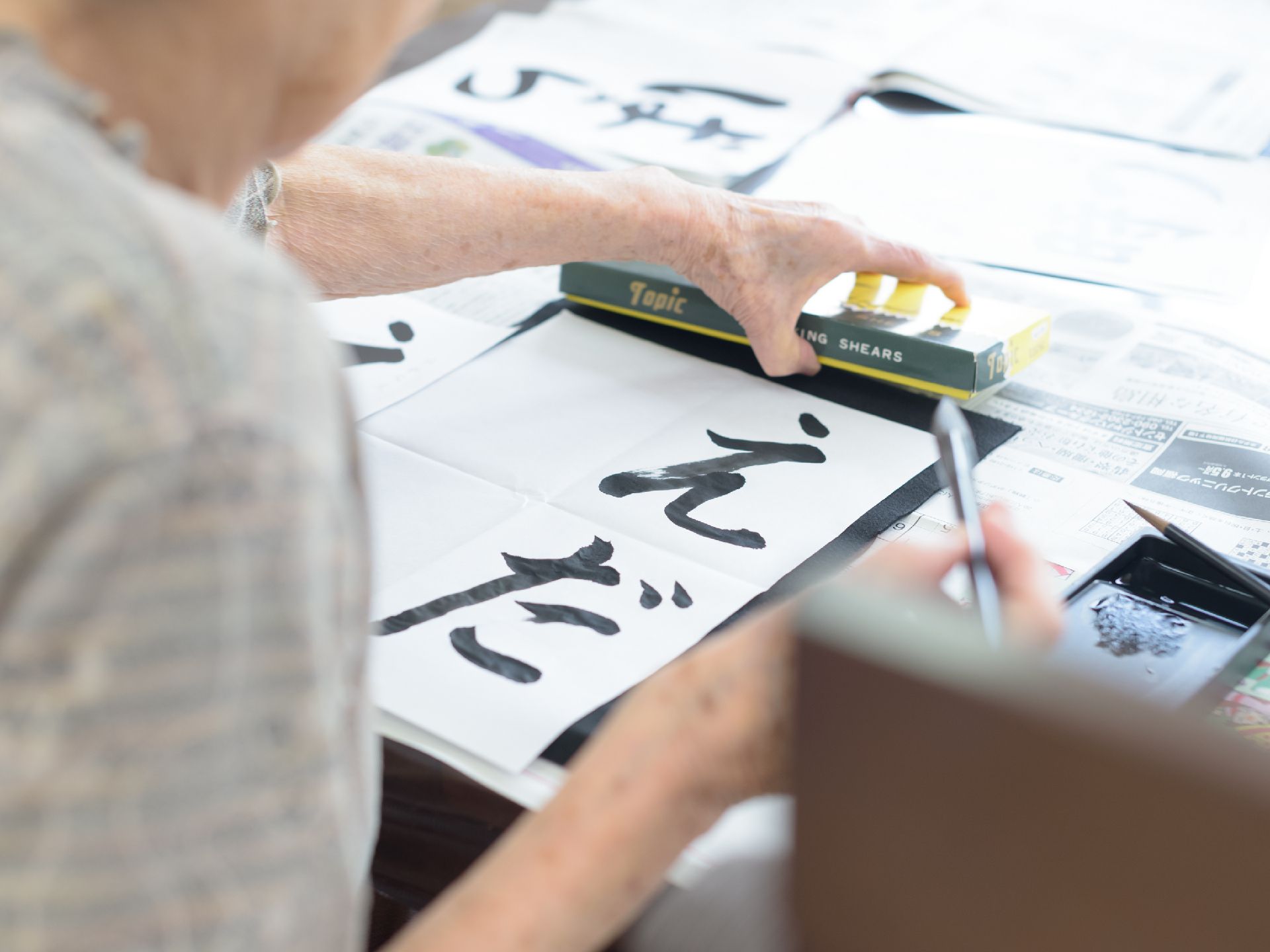 きれいな字で書道をして過ごされている高齢男性の様子