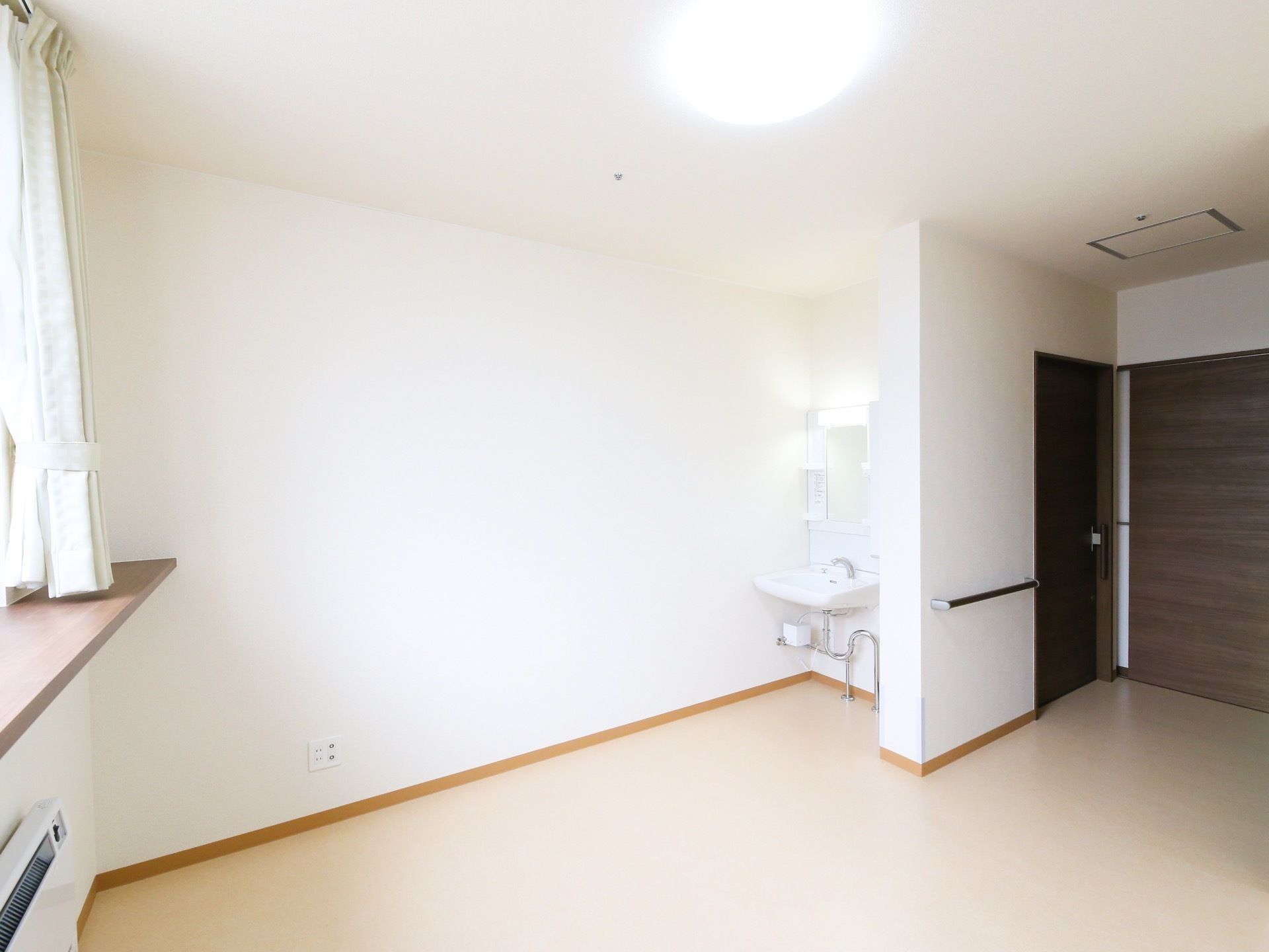 白を基調とした明るい個室で、部屋の角に洗面台がある。居室に入ってすぐの場所にトイレが設置されている。