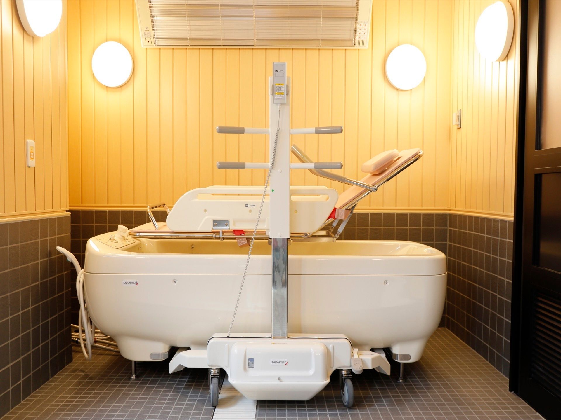 寝位入浴の可能なストレッチャーと特殊浴槽が置かれている。壁には４か所に丸い照明が取り付けられている。
