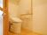 温水洗浄便座が設置されたトイレで、壁に操作パネルが取り付けられている。パネルの下には非常ボタンが用意されている。