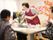 エプロンをしている女性スタッフが大笑いをしていて、テーブルには入居者たちが座っている。