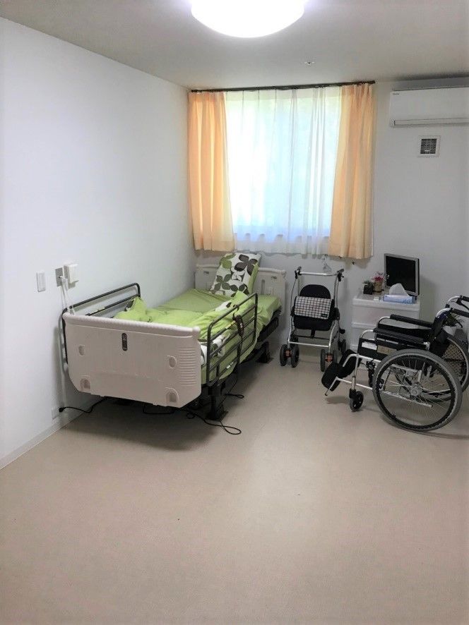 ベッドや車いすが置かれた居室。段差がなく大きな窓の横にはエアコンもある。