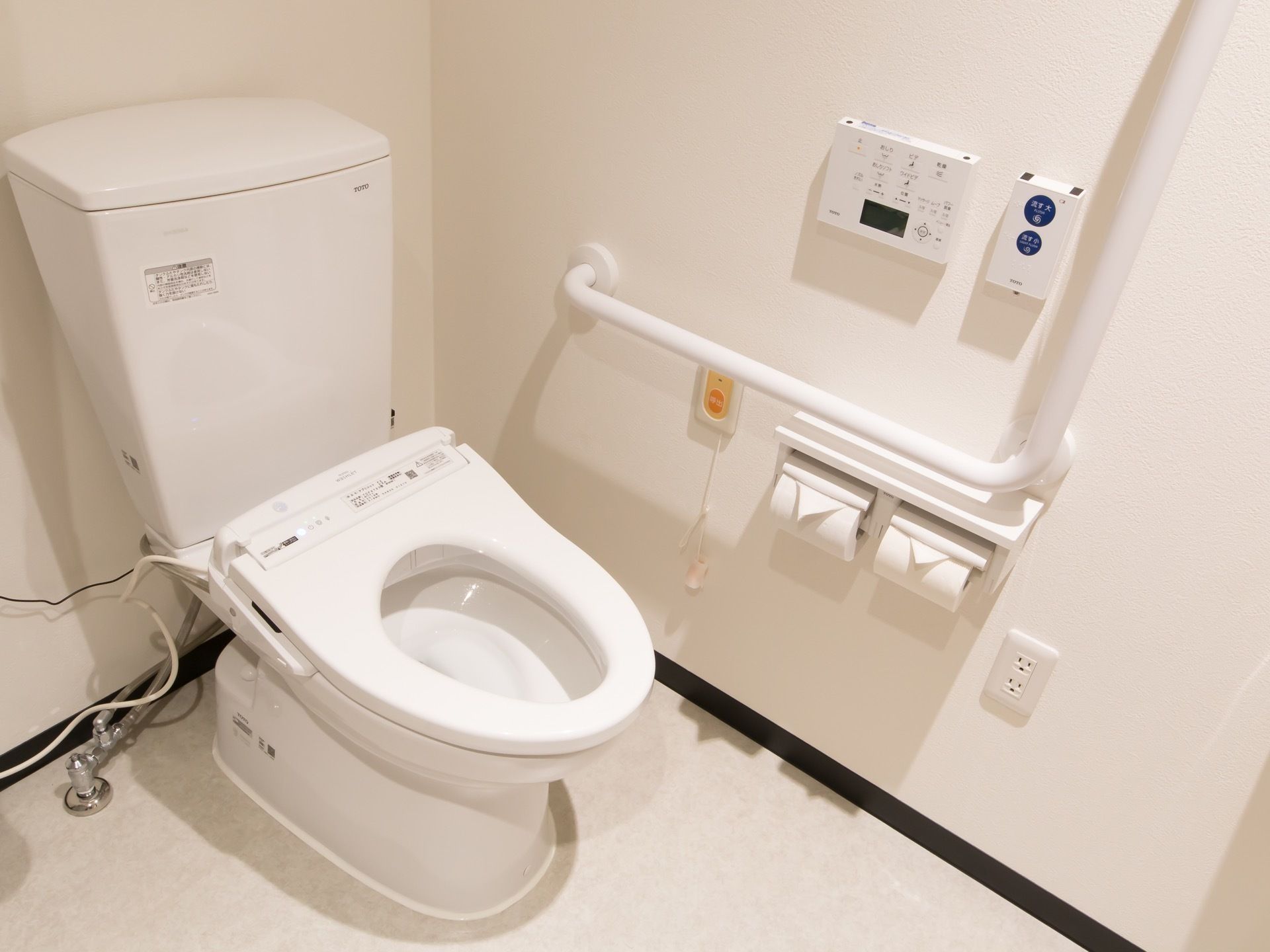 洗浄暖房機能つきのトイレがある。便座に座って左側の壁に、便座の操作ボタンやナースコールボタンがある。
