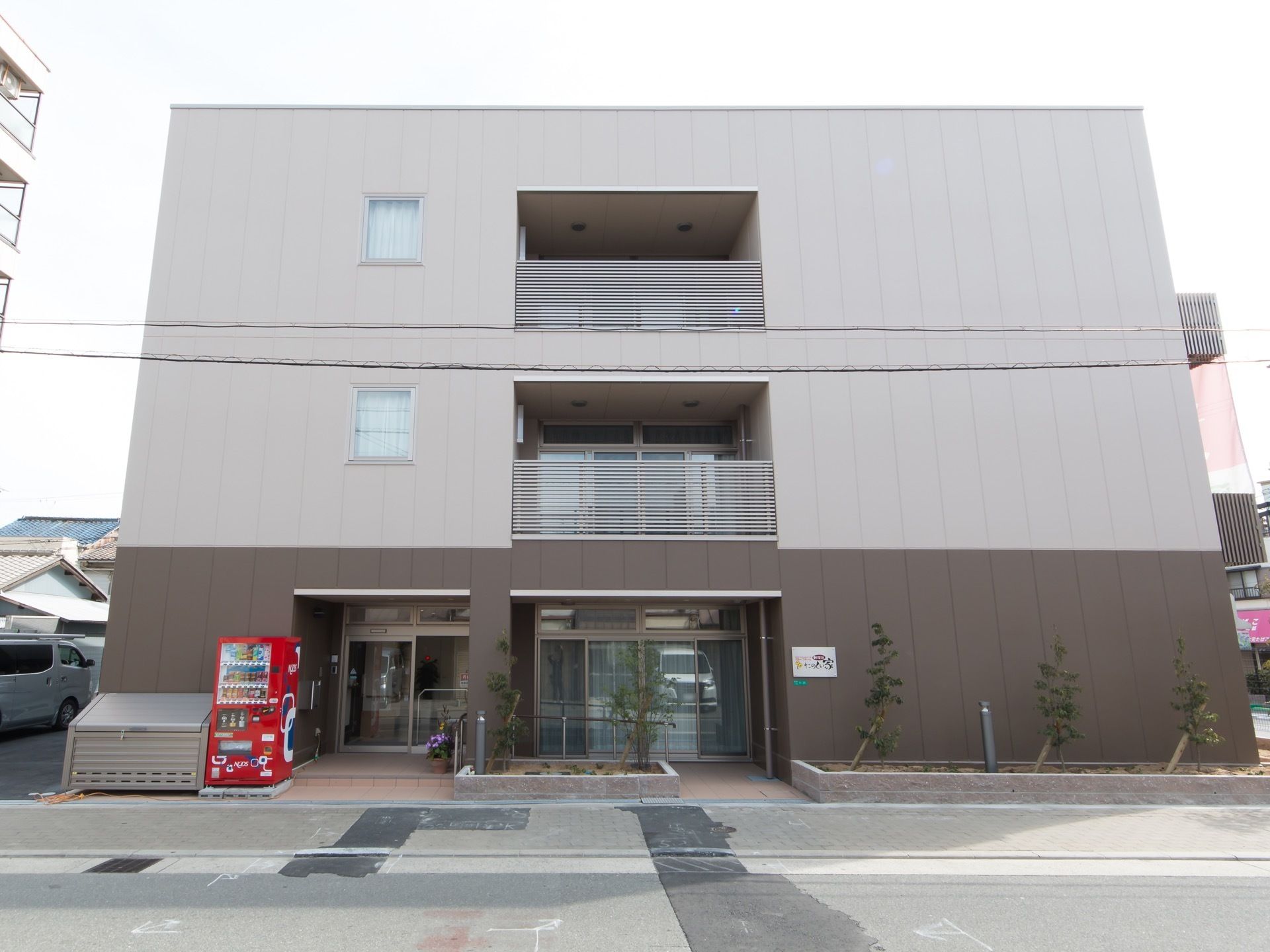 ツートンカラーの外壁の３階建ての施設である。２階と３階には道路に面した側にバルコニーが設けられている。