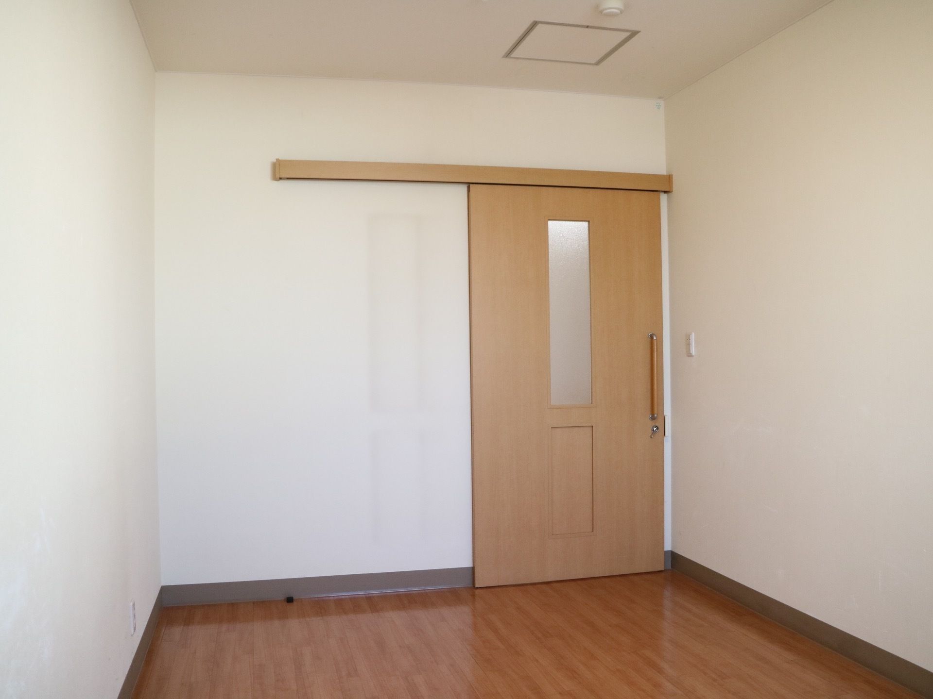 白い壁とフローリングの床になっている明るい居室である。出入り口の扉はスライド式で大きな取っ手があり、小さな力で開閉することができる。