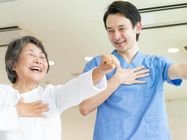 手の運動をするリハビリ中の高齢女性と指導をする理学療法士の男性