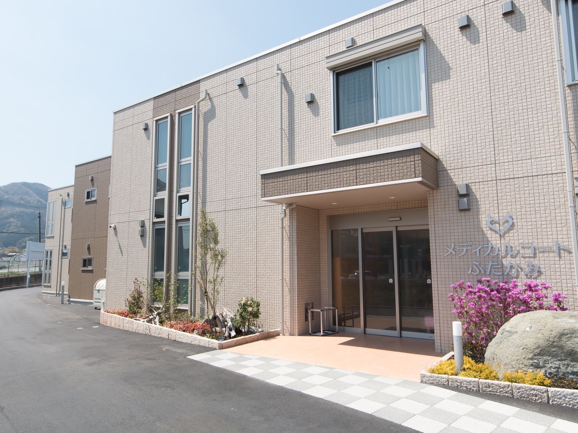 施設は2階建で、玄関口に大きく施設名が書かれている。モニュメントとして大きな石が置かれており、その側には花が植えられている。