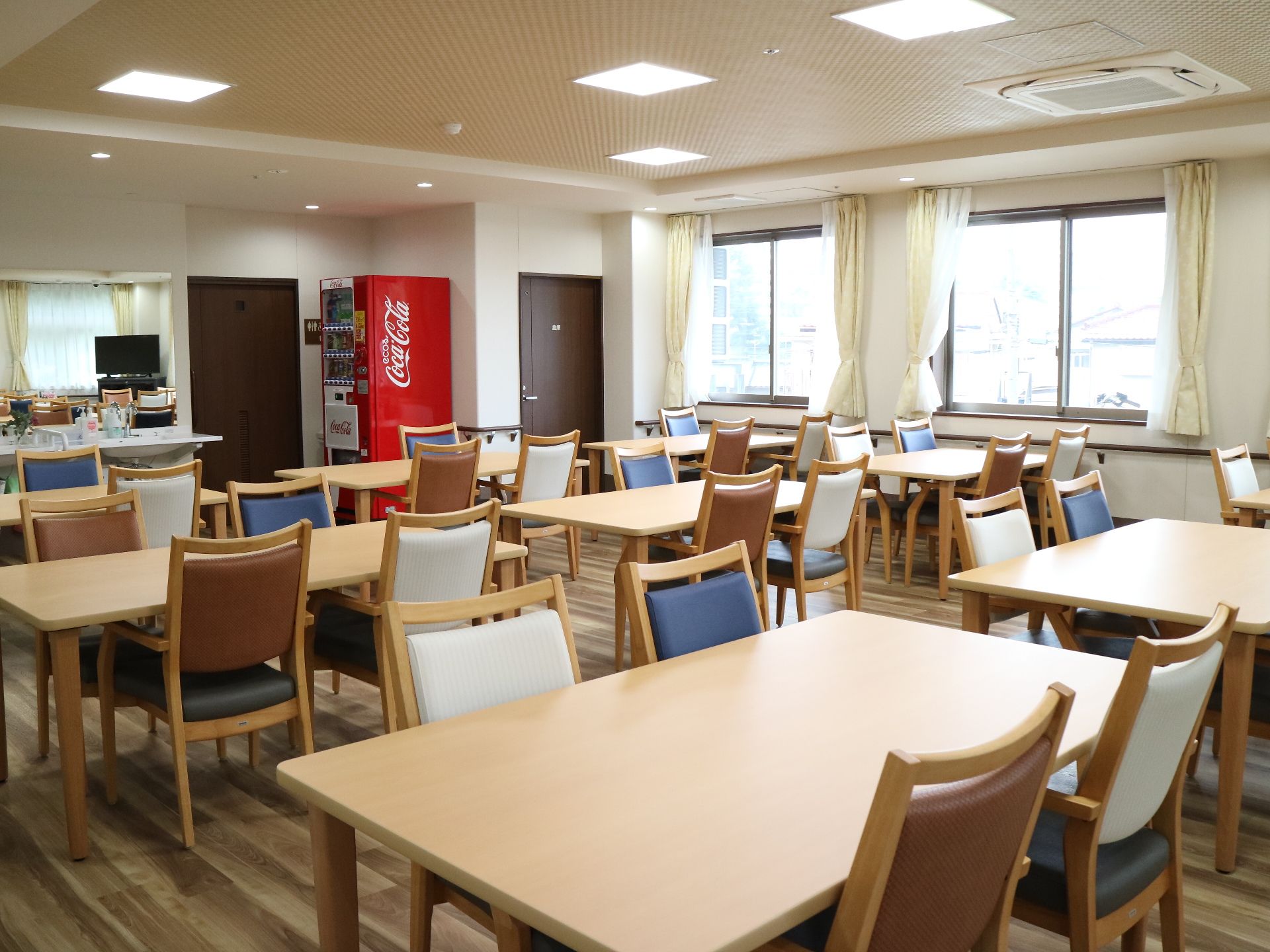 青、白、茶とカラフルな椅子が並べられている食堂スペース