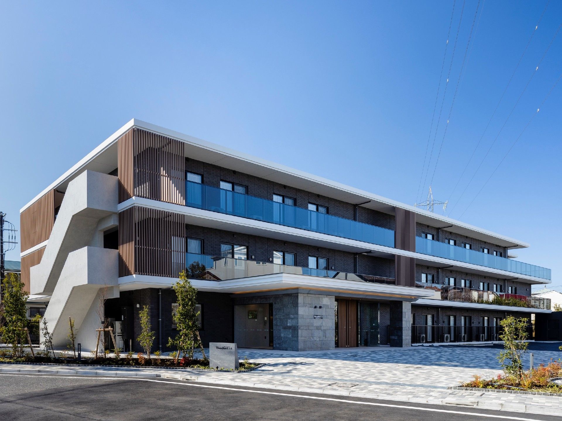 3階建ての建物には駐車場が付き、各フロアにベランダがある。周辺には緑も多い。