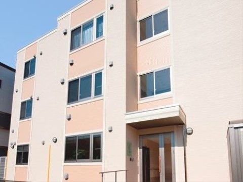 ベージュ系のツートーンカラーの外壁の3階建ての施設外観