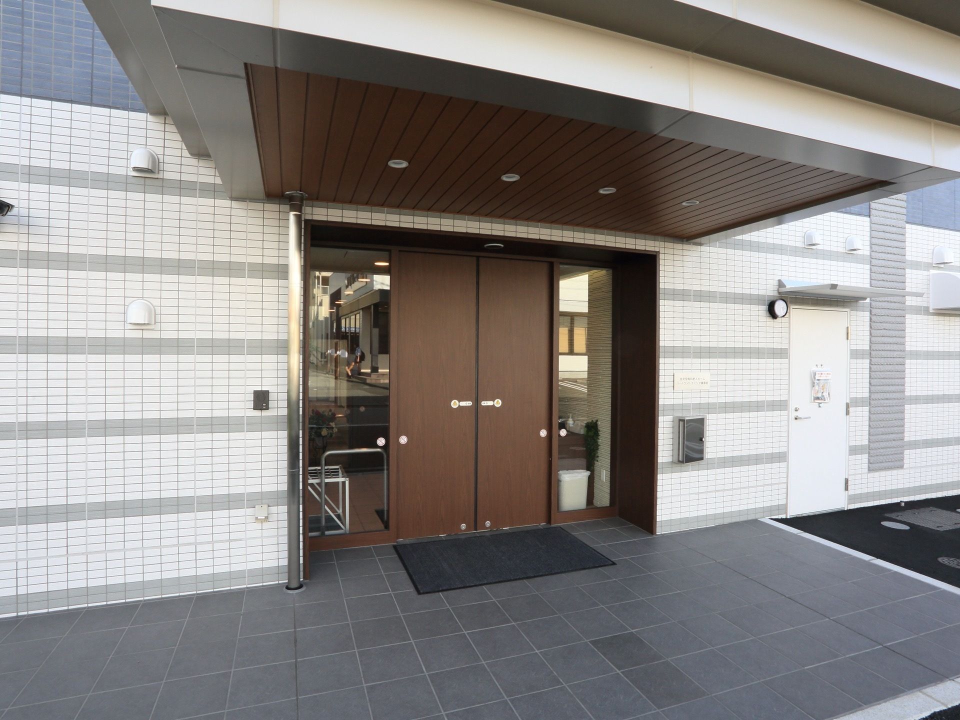 施設入口には、エントランスポーチが設けられている。照明器具が設置され、両開きの自動扉が完備されている。