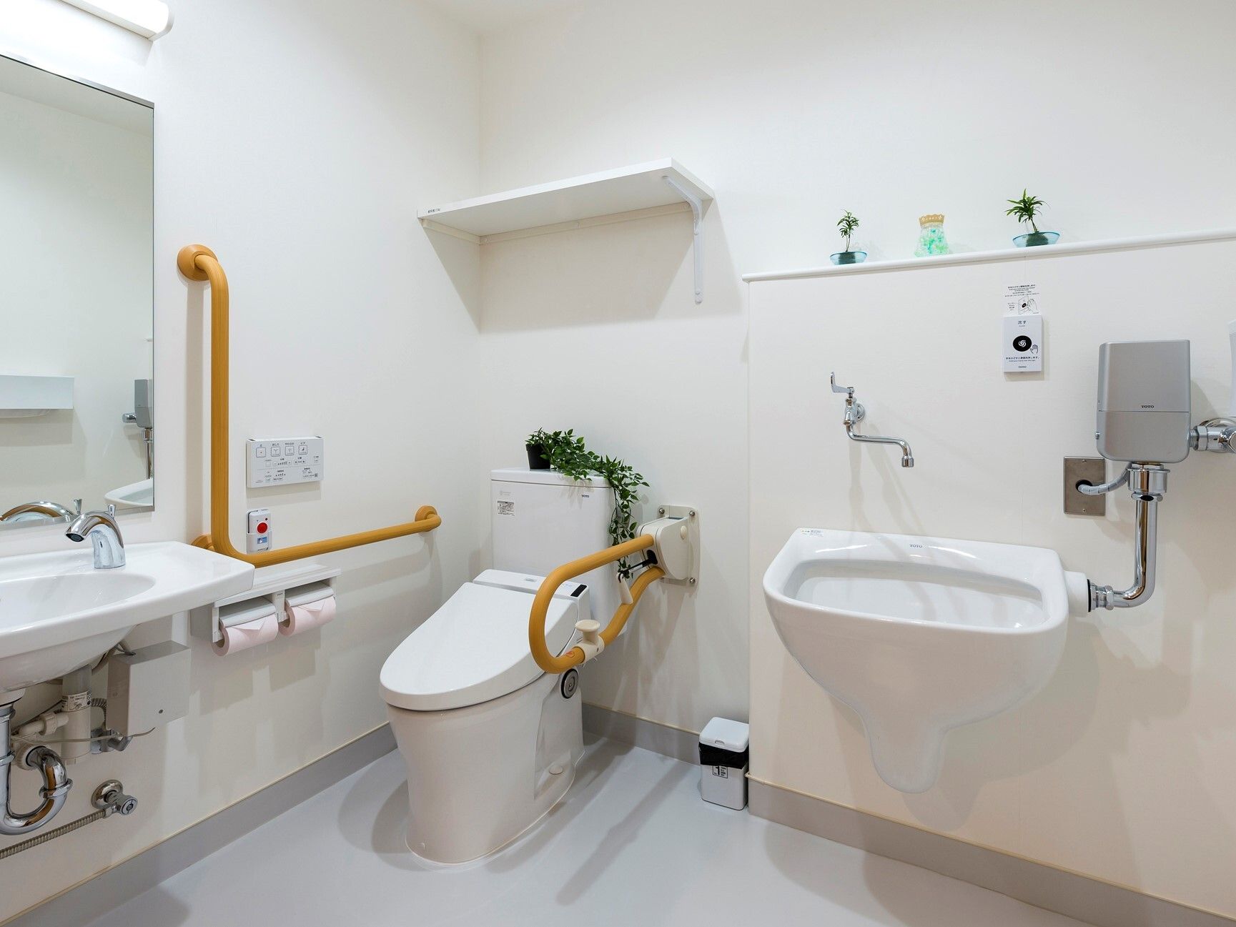 汚物処理専用機器が完備されたトイレである。温水洗浄便座器のそばには、可動式手すりやL字型手すりが設置されている。