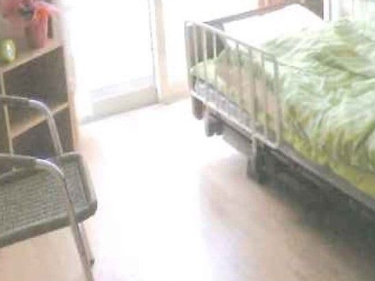 一人用の小さな部屋にベッドとタンス、いすがある様子。施設内の一室