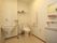 白色をベースとした広く清潔感のあるトイレである。上部に備品が置ける棚があり、便器の両脇に手すりが設けられている。
