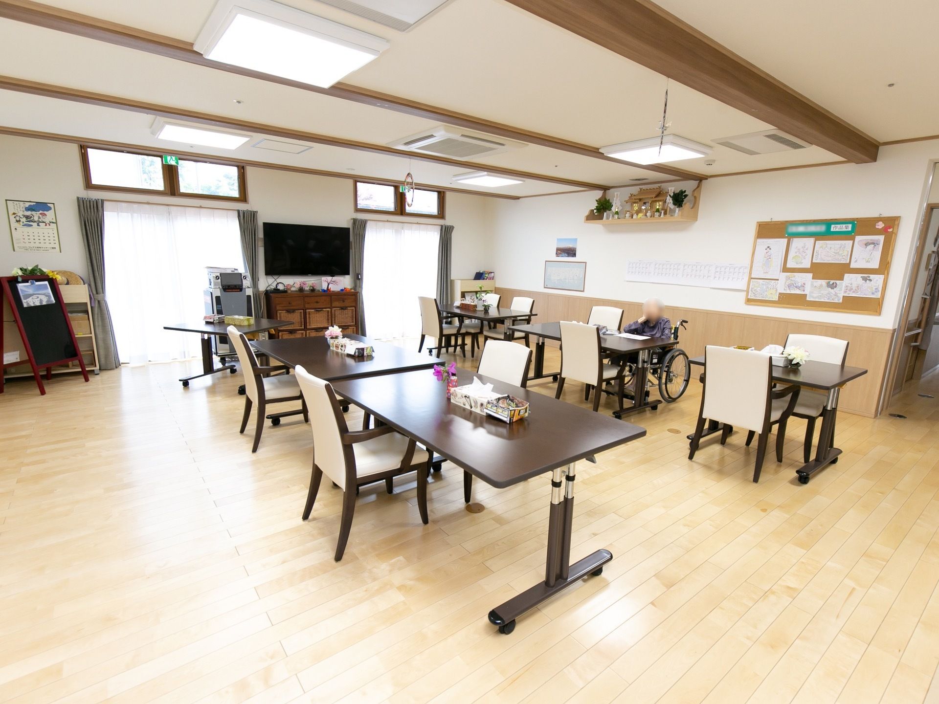 高さを変えることのできる４人掛けと２人掛けのテーブルが、２列に配置されている。白い肘掛け椅子が用意されている。