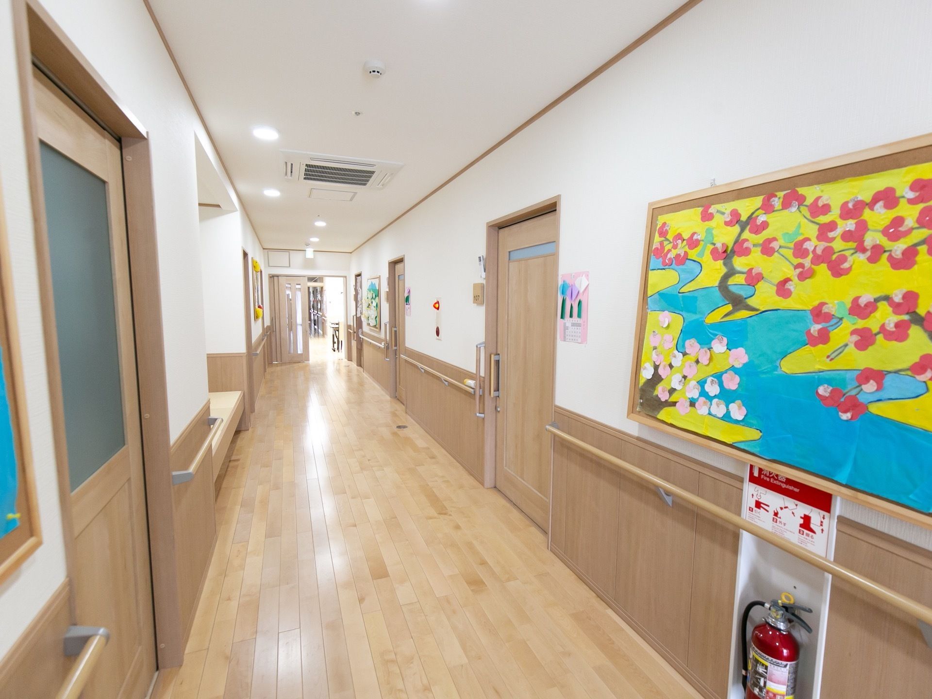 居室のドアの間には、コルクボードが貼ってあり、絵が展示されている。画用紙や折り紙で、川や花の咲いた木が描かれている。