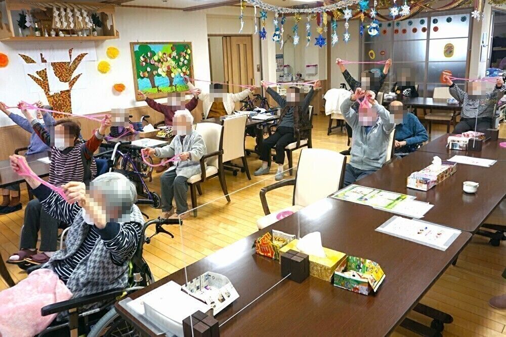 濃い茶色のテーブルと白い背もたれの付いた椅子が配置された共有スペース