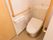 手洗いタンク付きのトイレである。L型とI型手すりが備えつけられている。床はバリアフリーになっている。