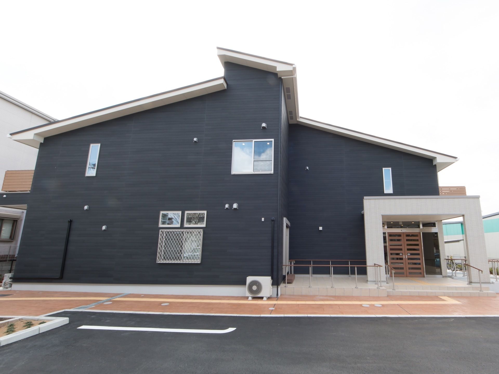施設は２階建てのシックな建物である。駐車場から玄関扉まで誘導ブロックが設置されている。エントランスには、階段とスロープが設けられている。