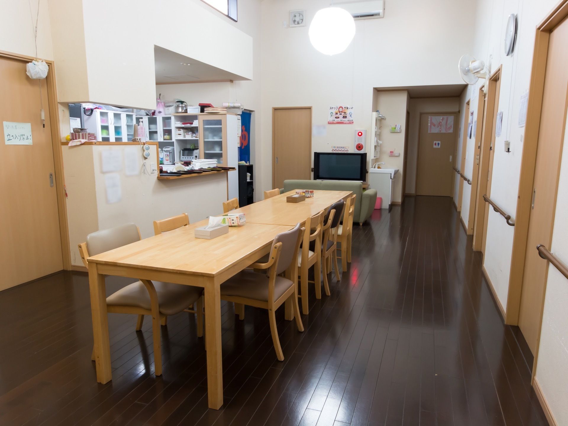 食堂の奥にはカウンターキッチンが設置されている。壁際には収納棚が並んでいて、オーブンなどが置かれているのが見える。