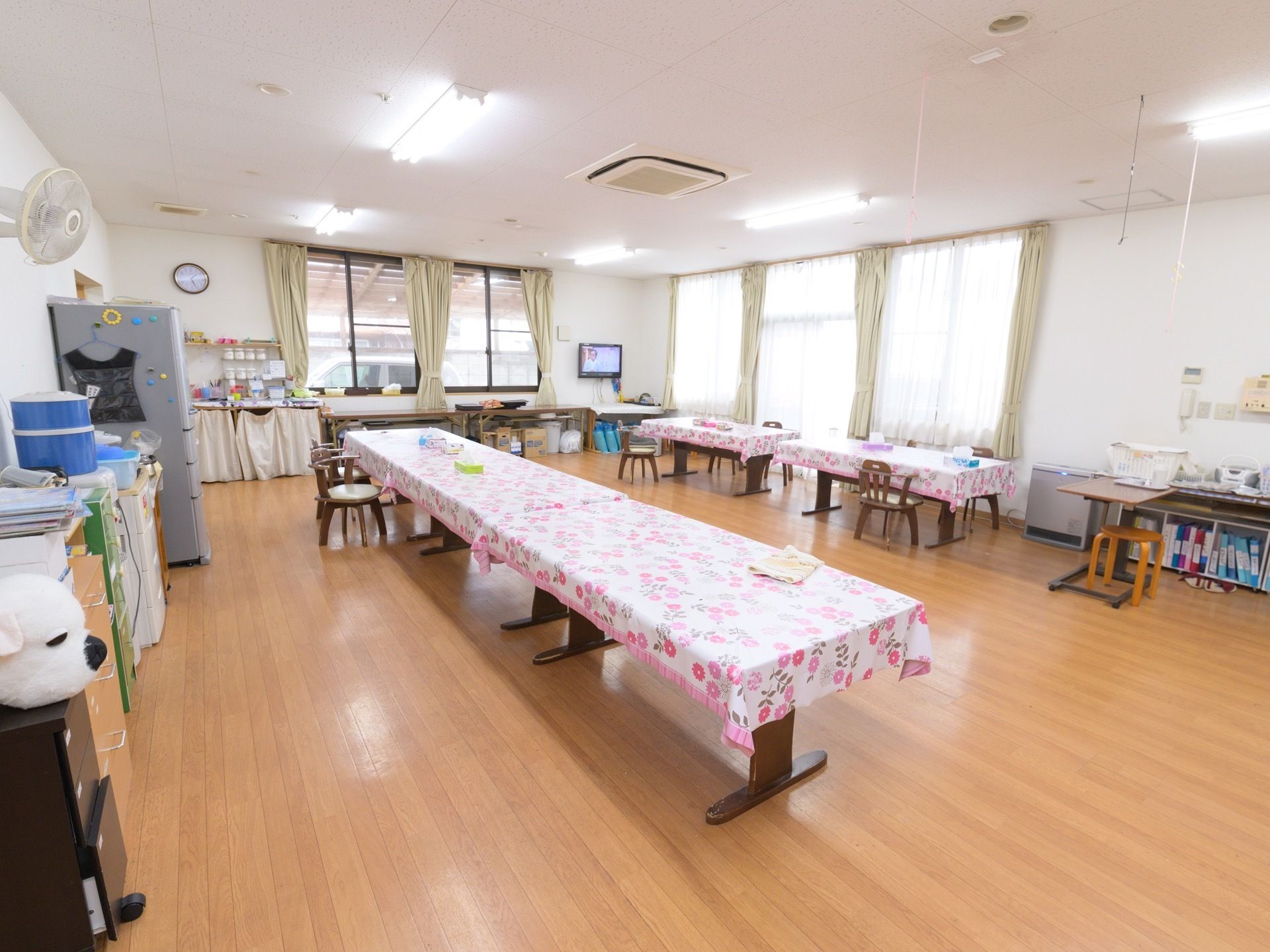 食堂では、ダイニングテーブルに可愛らしいデザインのテーブルクロスが掛けられている。冷蔵庫が置かれているのが見える。