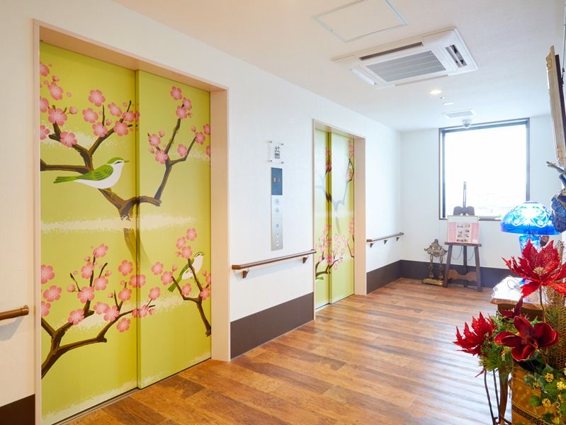 鶯色のエレベーターの扉には満開の購買と鶯が描かれ、館内にもたくさんの花が飾られている。
