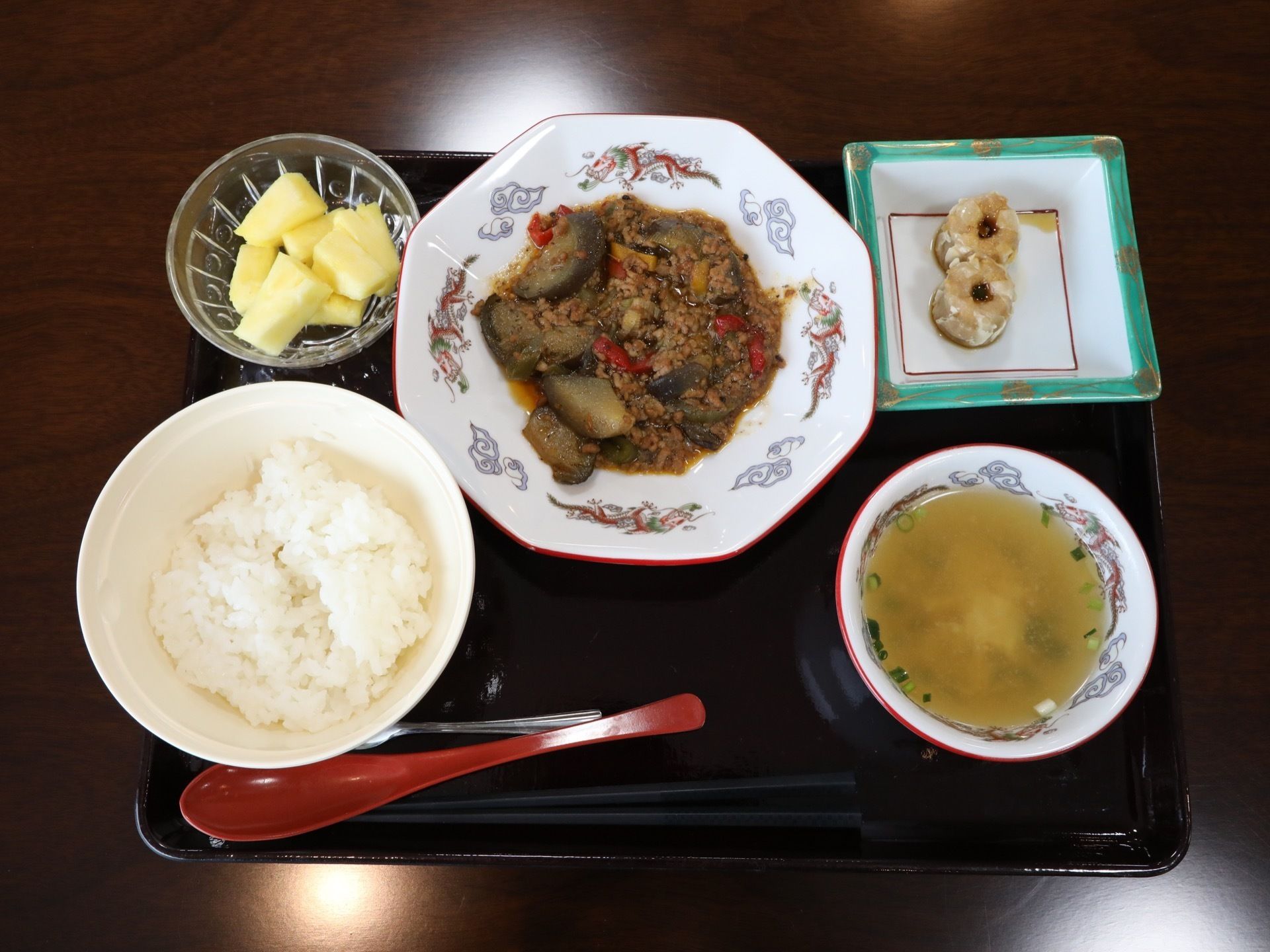 ご飯、スープ、主菜と副菜の他に、食後のフルーツが載っている。箸やフォークの他に、レンゲも用意されている。