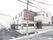２階建ての建物で外壁には白とブラウン、ベージュが使われている。出入口にスロープと階段が設けられている。