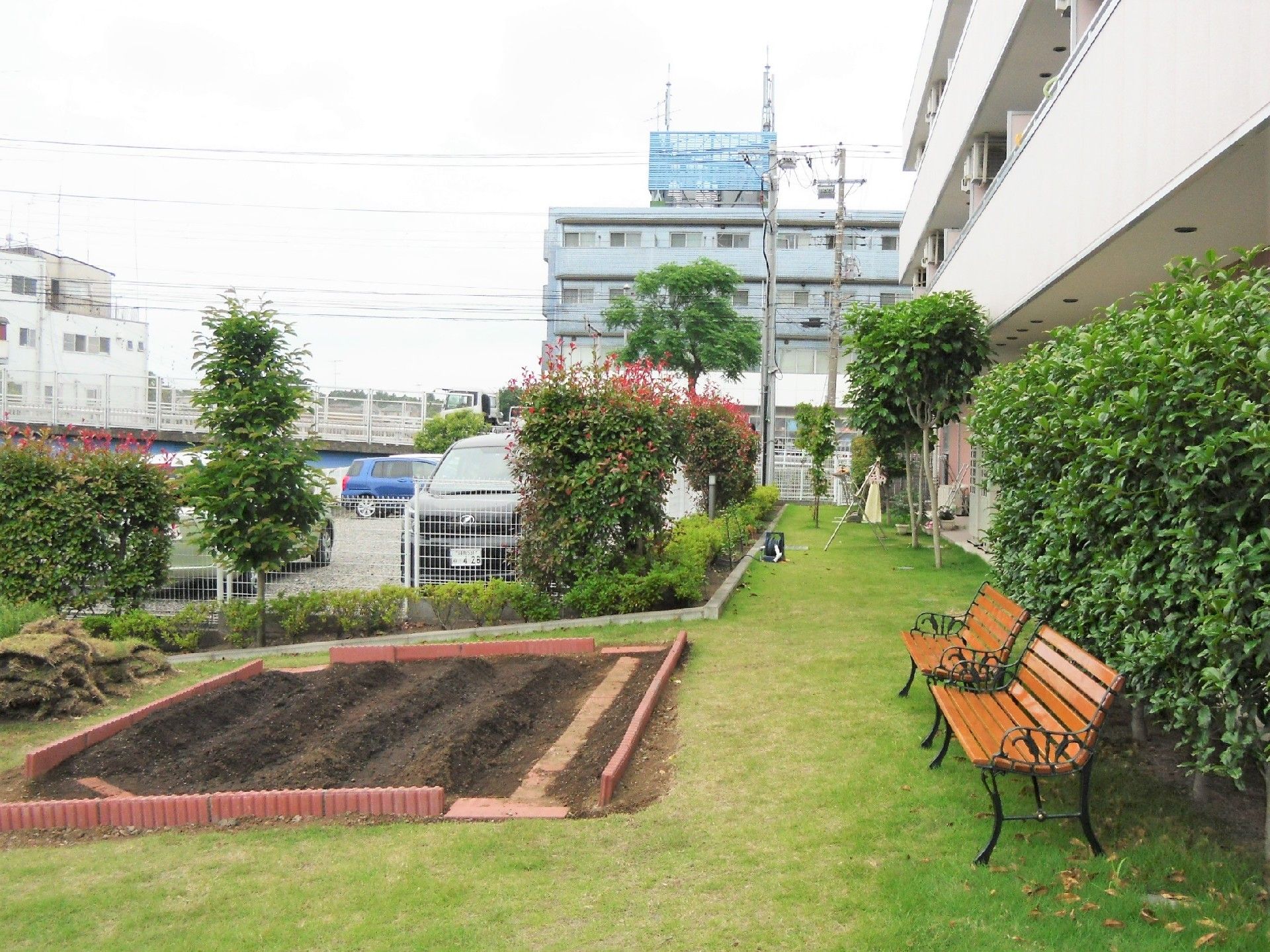 緑色の芝生と花壇。横には木製のベンチも設置されている。