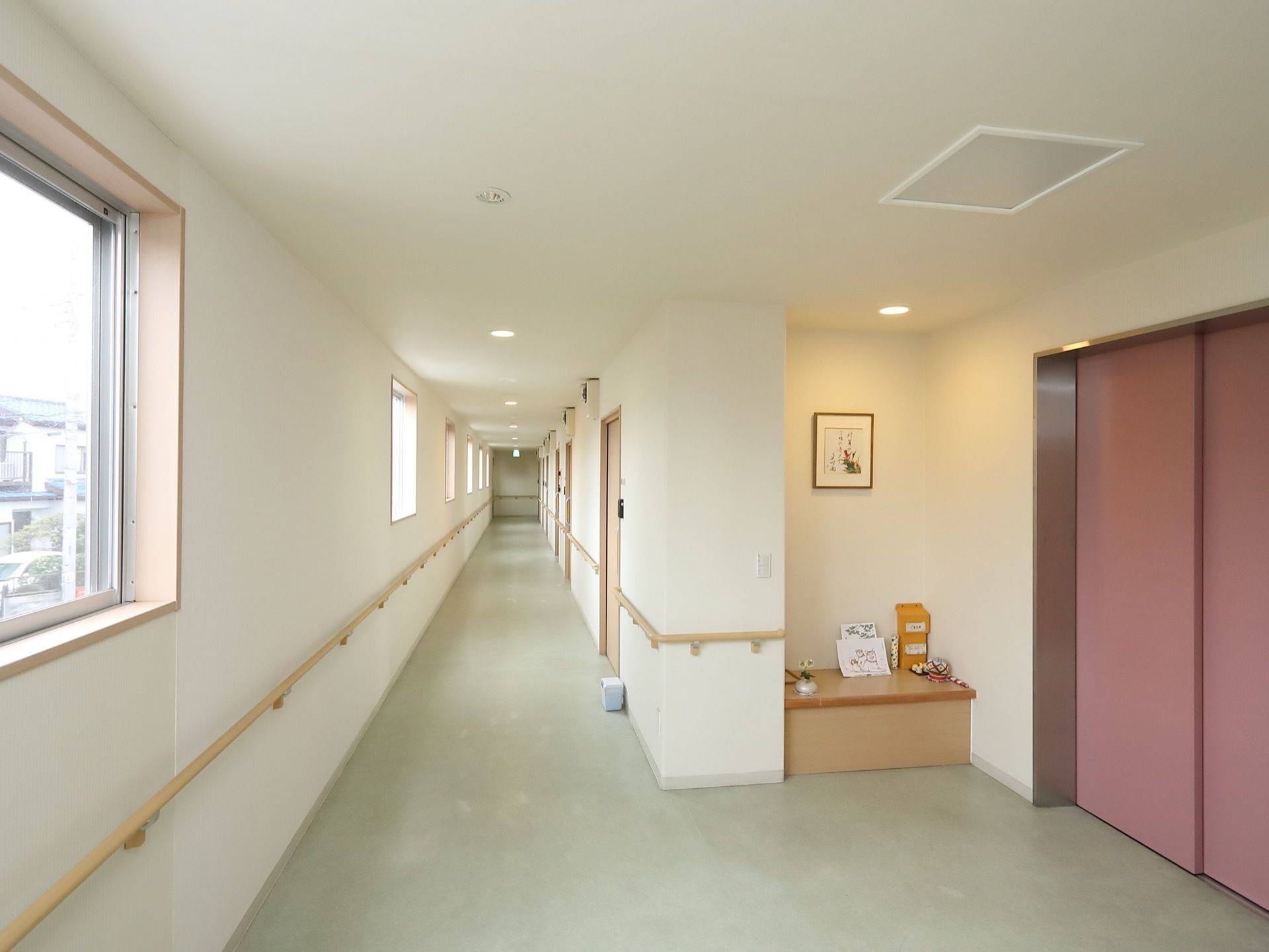 廊下は、多くの窓からの採光で明るくなっている。壁には、居室の入口以外に切れ目なく手すりが設置されている。