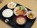黒いお盆に、おかずが３皿とご飯、みそ汁が置かれている。おかずは、揚げ物、野菜の煮つけ、マカロニサラダである。