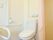 居室に備え付けられたトイレは、カーテンで仕切られており、Ｌ字型の手すりが設置されている。段差がないため、出入りがスムーズに行える。