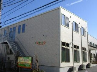グレーの2階建ての建物は玄関には大きな看板があり、外壁にはホーム名が書かれている。