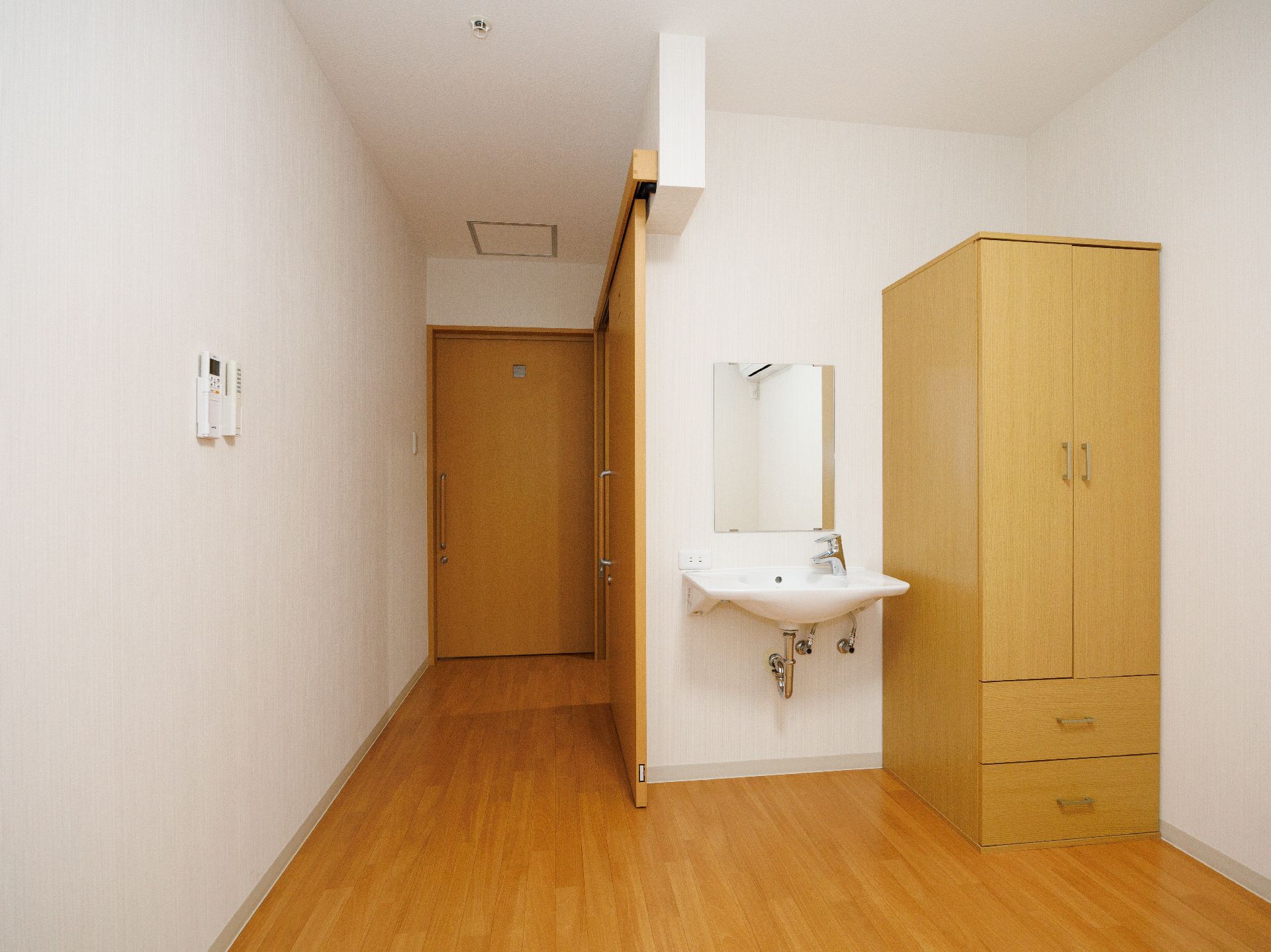 洗面台と木製の棚が置かれた白い壁の部屋
