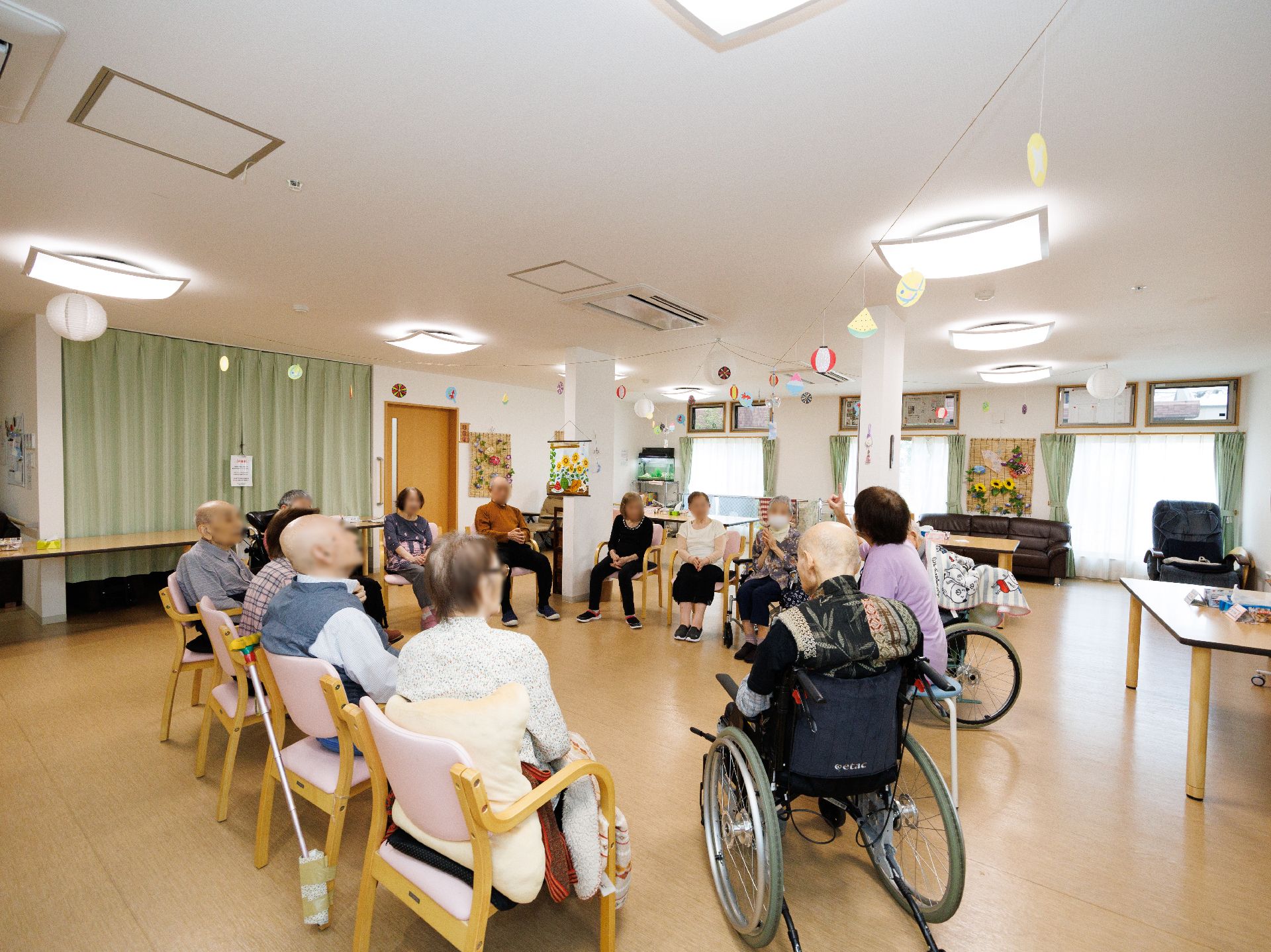 椅子に座った入居者様が円になって集まっている広間