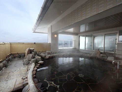 円形の浴槽が屋外に設置され、浴槽のふちには石があり、浴槽への出入り木地には手すりも付いている。
