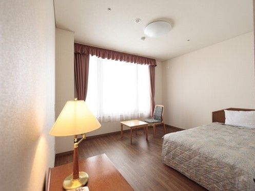フローリングのシンプルな居室は高級感がある。タンスやカーテン付きの窓、寝具付きのベッドなどが付いている。