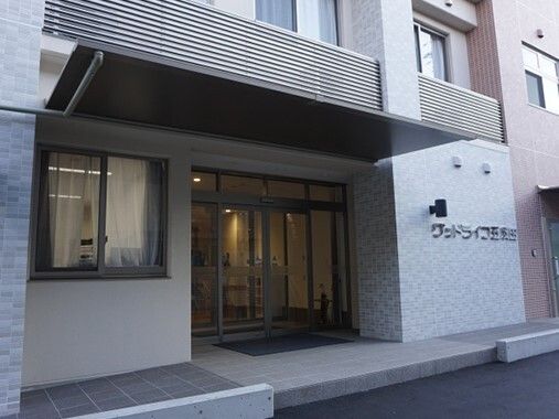 外壁にはホーム名が書かれ、玄関には自動ドアやマットが設置され、館内は暗い。