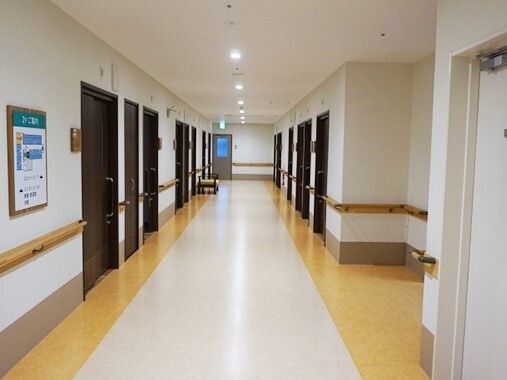 まっすぐな廊下の両サイドに手すりが付き、居室のドアが設置されている。壁にはフロアの見取り図がある。