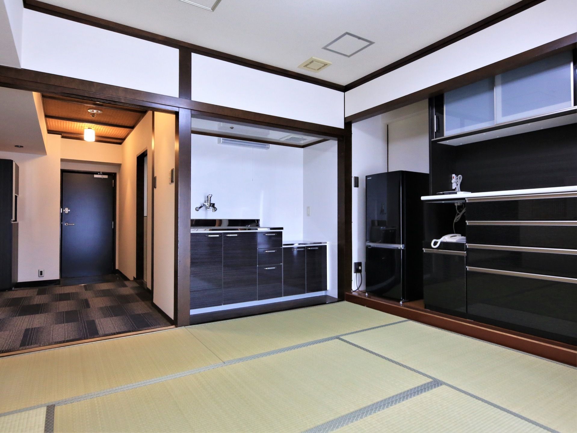 黒いキッチンやキッチンボードが設置された居室。和室になっているため、洋室が苦手な入居者様も安心することができる。