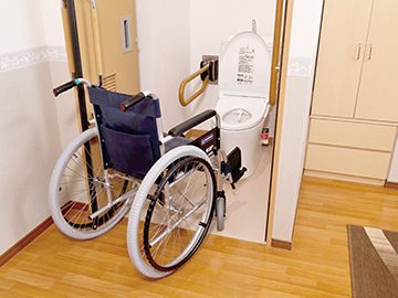 トイレのドアを開けた状態で車いすが置かれ、トイレには可動式の手すりが付いている。