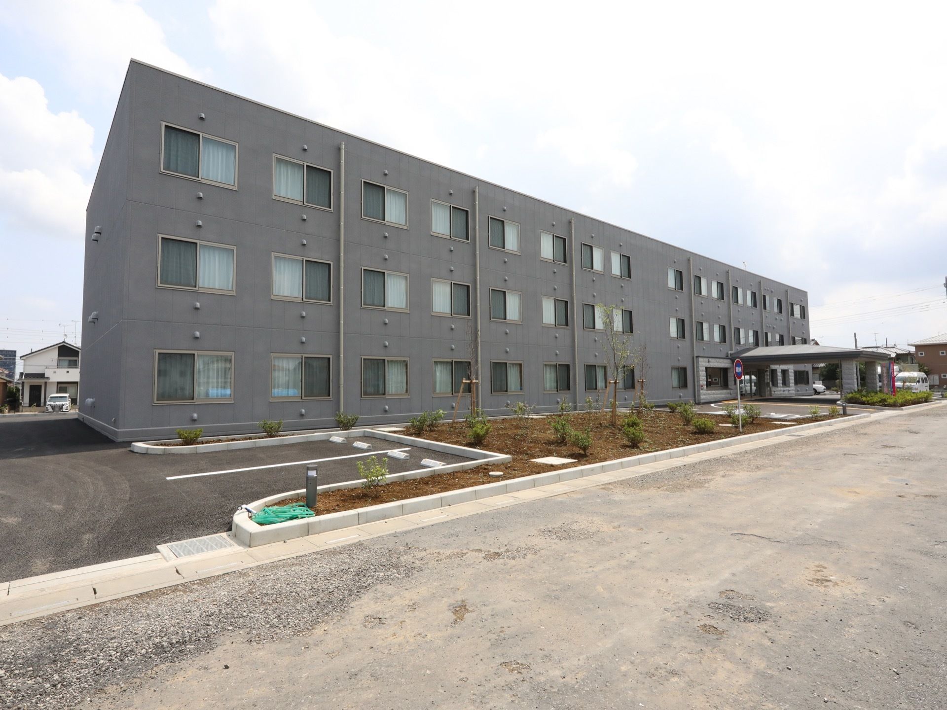 施設は３階建てで、規模が大きいものとなっている。敷地はアスファルト舗装で、そこには広い駐車場を用意。