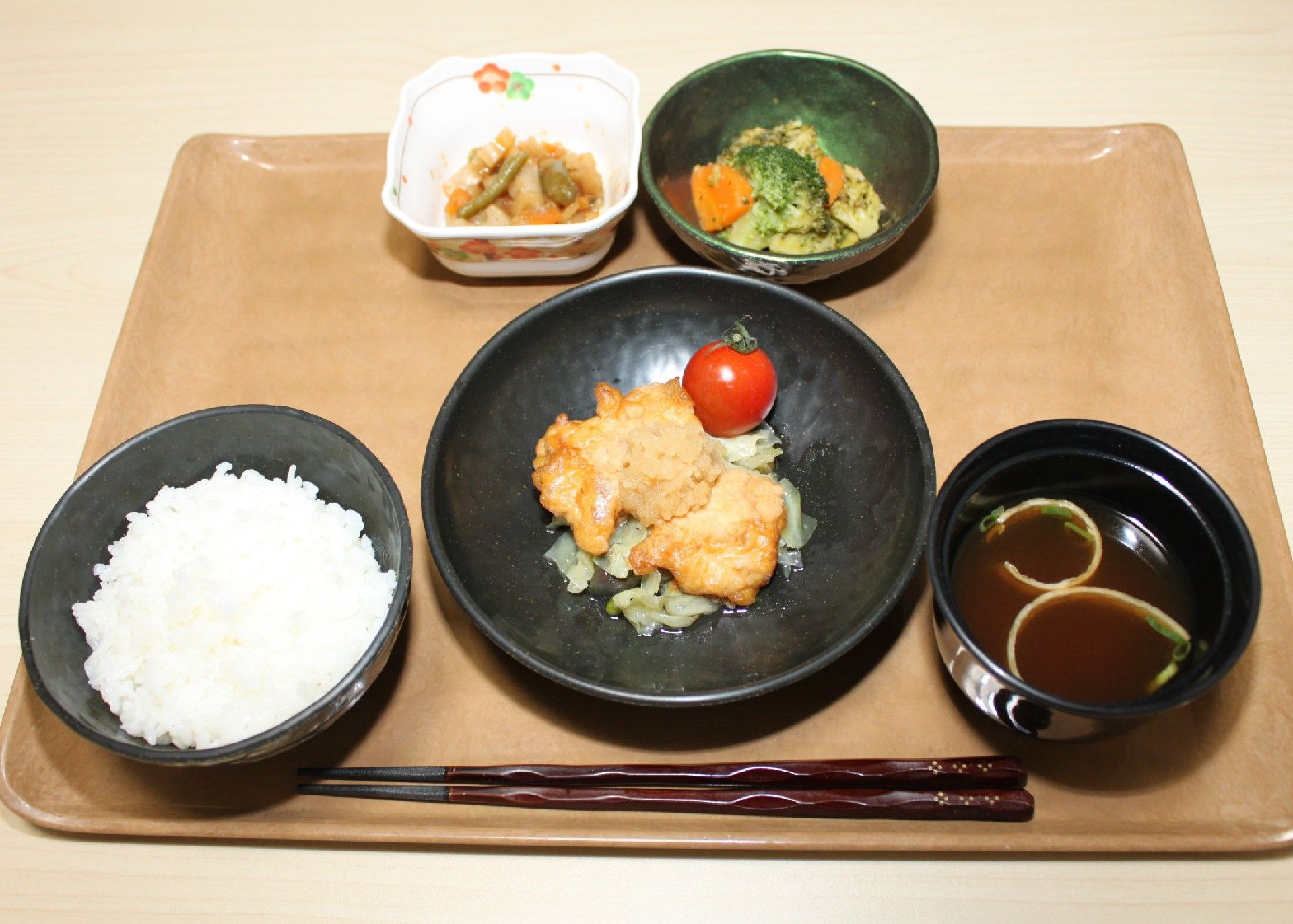 トレイの上には白いご飯やみそ汁、メインのとり肉料理に小鉢に盛られた煮物と青菜の和え物がある。