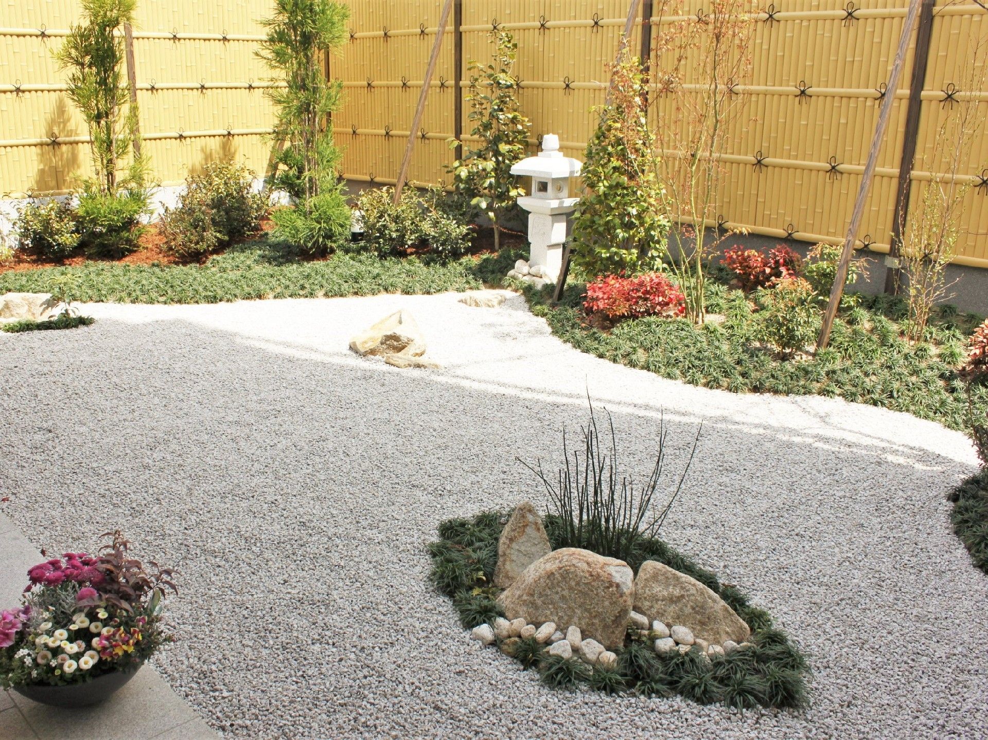色とりどりの花が咲いている庭にはたくさんの木もあり、竹でできた柵がある。