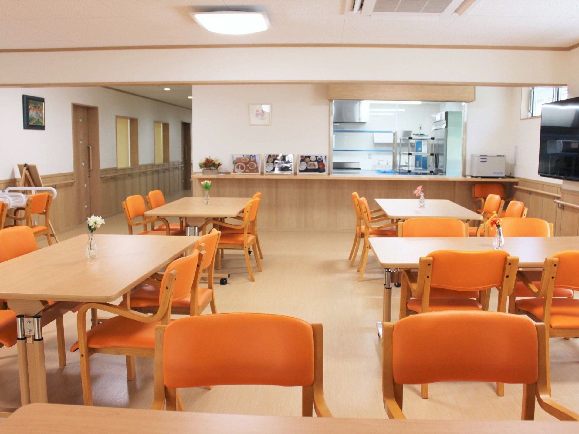 木製のテーブルが置かれ、テレビコーナーもある。明るい食堂は木のぬくもりが感じられる空間。