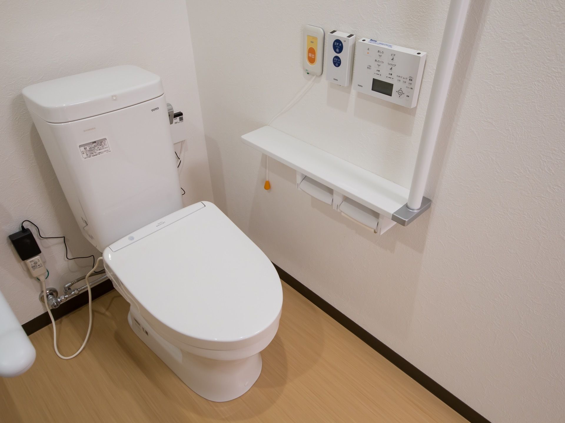個室トイレの内部。便座の左にある壁には手すりとペーパーホルダーが一体となったパーツが取り付けられている。