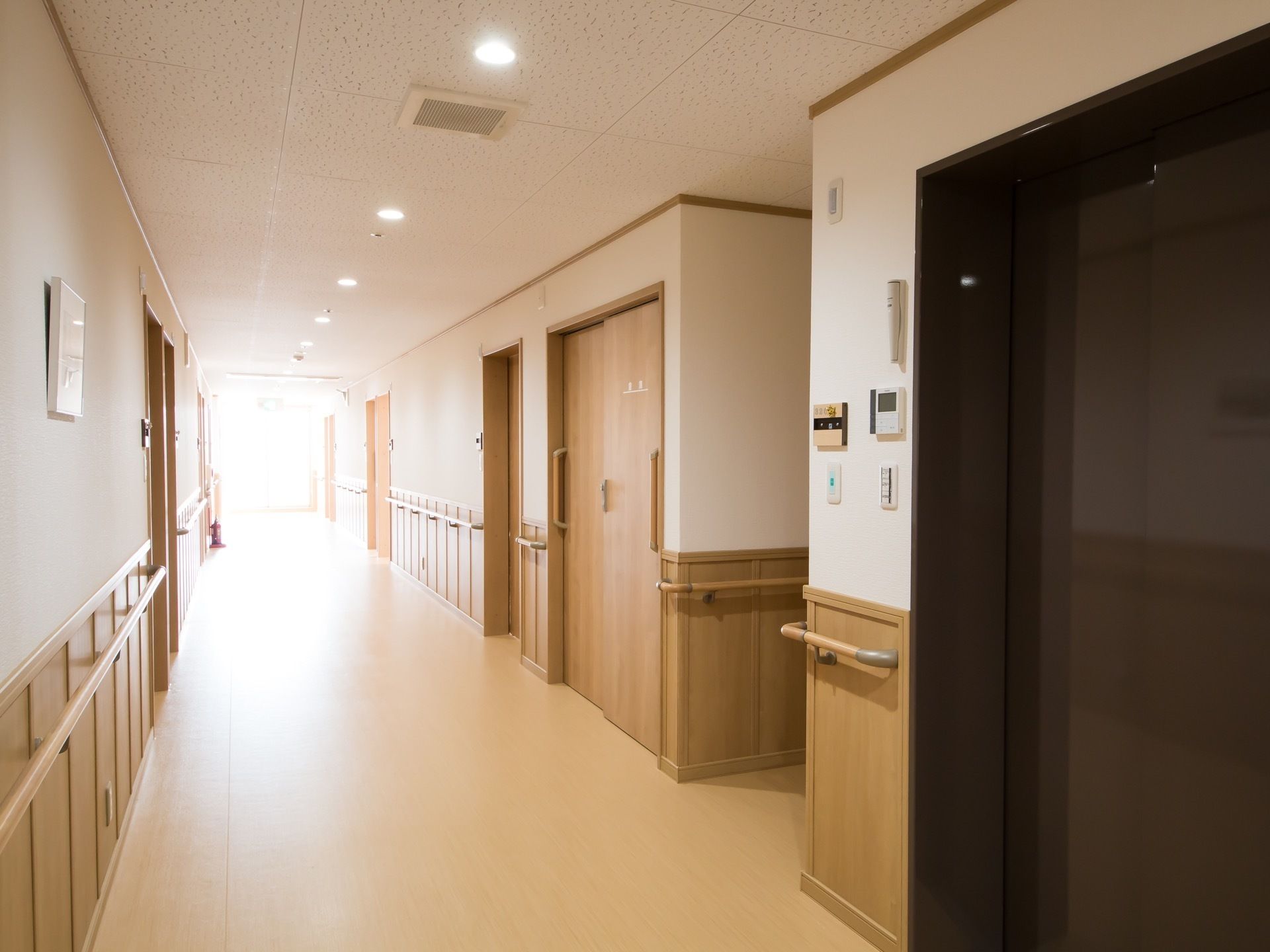 施設内にある廊下の様子。建物内を一直線に通っており横幅に余裕を持たせた構造で、左右には各居室が並んでいる。