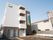 建物は４階建て構造になっている。正面にある道路に対してはベランダ付きの窓が向いている。外壁の一番上には看板がある。
